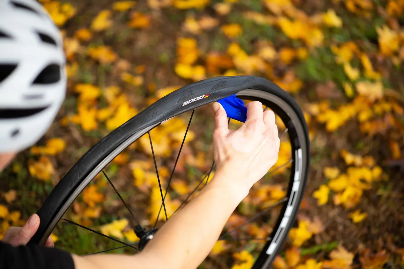 Hands using a tire lever on a bicycle wheel outdoors